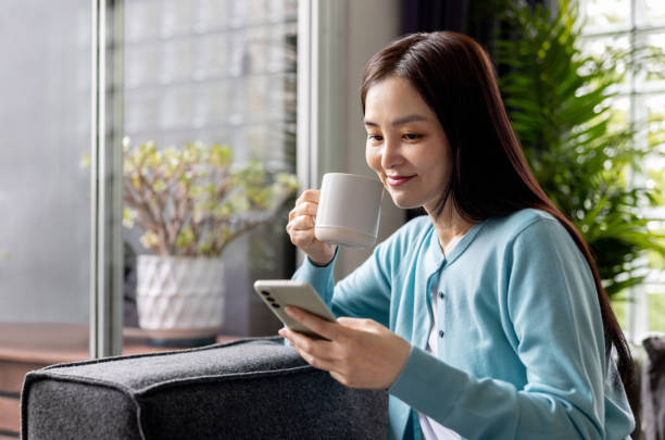 istock Woman relaxing at home drinking coffee while texting on her phone 2197466793