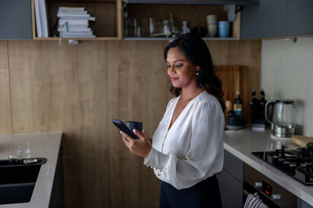 istock Happy businesswoman at home using her cell phone while drinking coffee 2197466841
