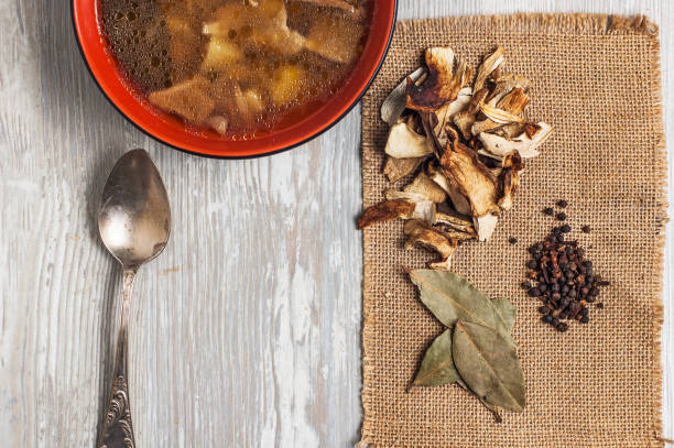 istock Mushroom soup with dried porcini mushrooms, bay leaf and pepper on rustic table texture background. 2197468141