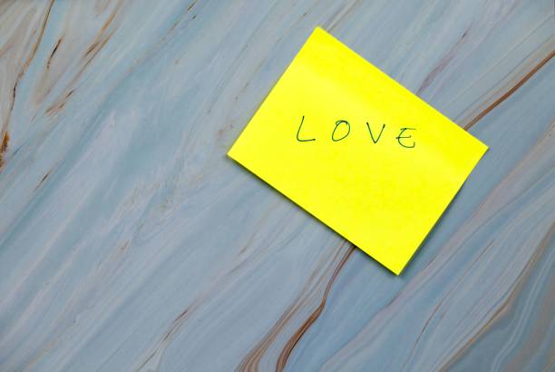 istock Yellow note with the word love on a blue marbled background, cre 2197469725