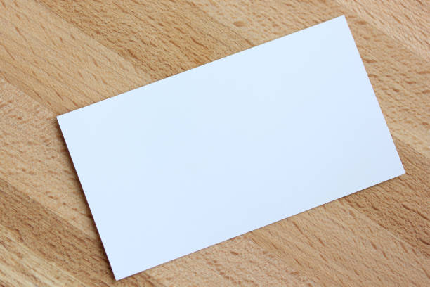 Business card mockup presenting a blank white card lying on a wooden table