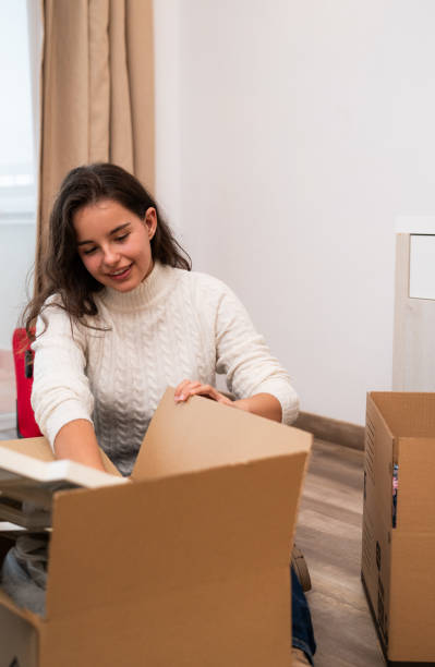 istock Young woman unpacking cardboard boxes in new apartment 2197475110