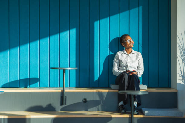 istock Woman Relaxing in Sunlit Modern Office Lounge Area 2197475740
