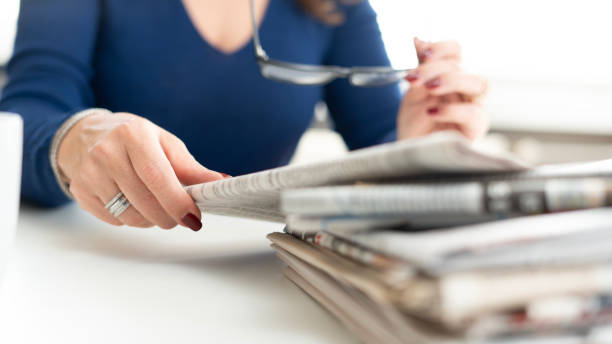 istock woman reading newspaper at office 2197476011