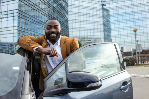 istock Confident man standing by car outdoors in modern urban setting 2197480805
