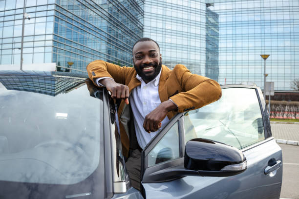 istock Confident man standing by car and looking at the camera in modern urban setting 2197480830