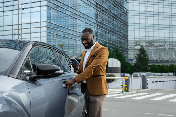 istock Man unlocking car using smartphone near modern car in urban setting 2197481399