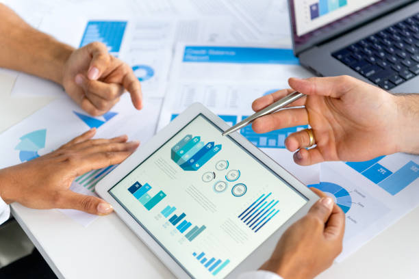 istock Close up of three people looking at financial data with graphs and charts. 2197481452