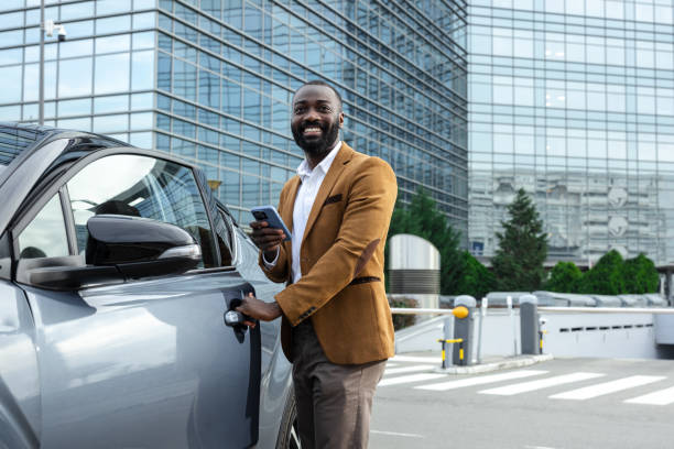 istock Man unlocking car using smartphone near modern car in urban setting 2197481459