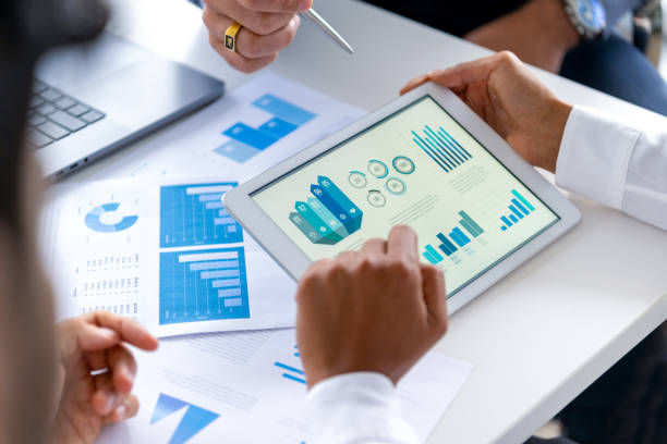 istock Close up of three people looking at financial data with graphs and charts. 2197481597