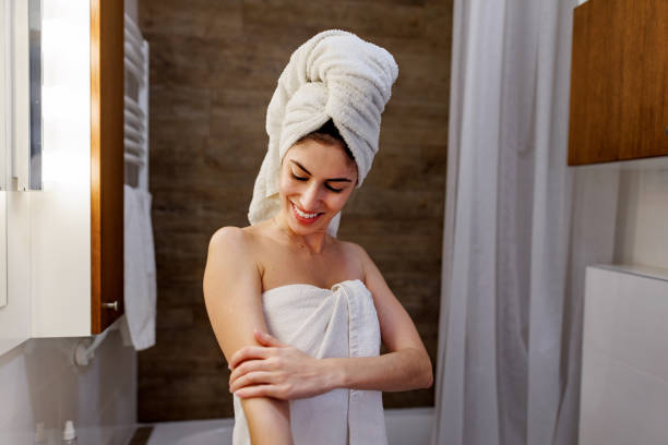 istock Young woman applying moisturizing cream on her arm after shower 2197492045