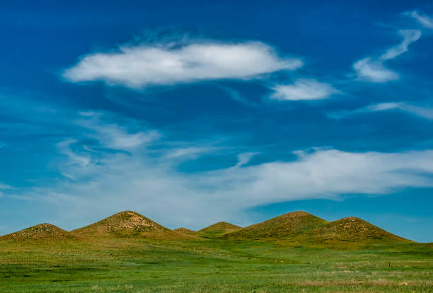 A photograph of an interesting landscape in South Dakota with a series of sharply pointed hills rising into a beautiful summer sky.