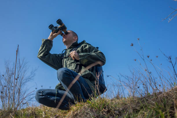 istock A young and handsome man with a large backpack on his back stands atop a mountain, gazing through binoculars at the distant horizons. He enjoys exploring the untouched nature, savoring every moment of his travel adventure 2197498374