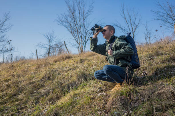 istock A young and handsome man with a large backpack on his back stands atop a mountain, gazing through binoculars at the distant horizons. He enjoys exploring the untouched nature, savoring every moment of his travel adventure 2197498382
