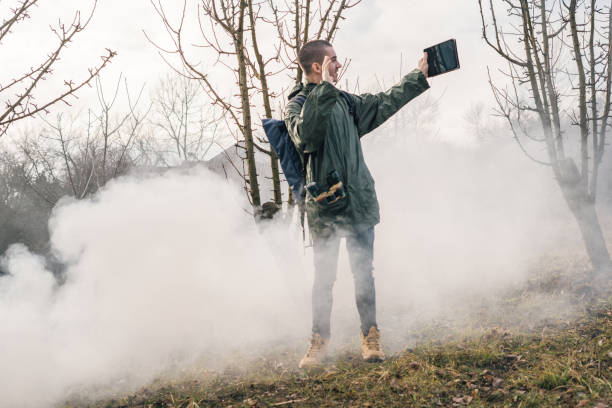 Young handsome hiker with open arm holds a singnal smoke flare