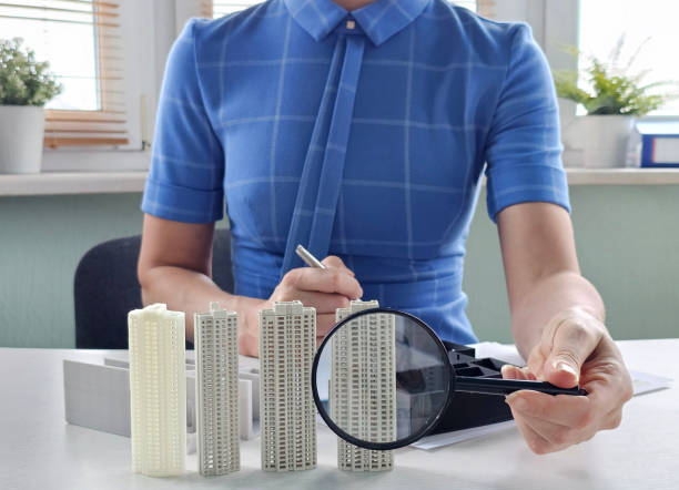 istock Analyzing architectural models and searching for buying and renting housing with the help of a magnifying glass concept 2197505312