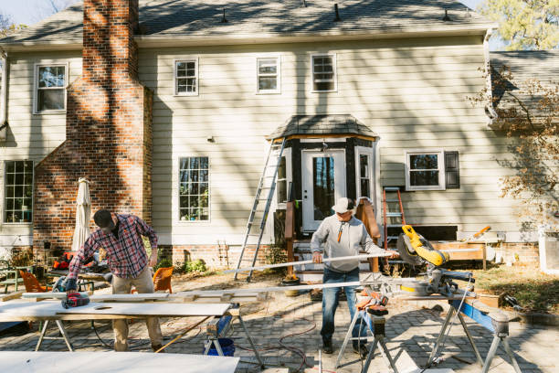 Father and son repair the siding of a colonial style house