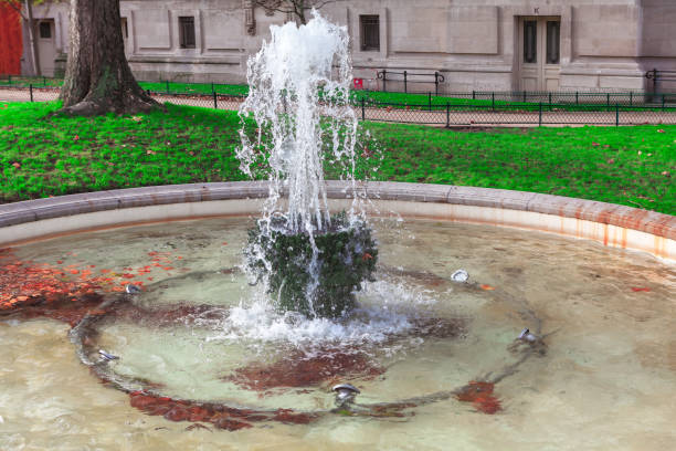 istock Small fountain in Paris with water gushing from stone structure 2197507074