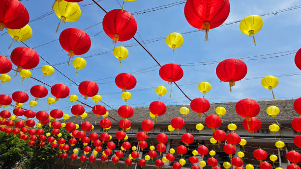 istock Vibrant red and yellow lanterns suspended across open balconies under a serene blue sky, representing festive celebrations of chinese new year and traditional cultural decor 2197507348