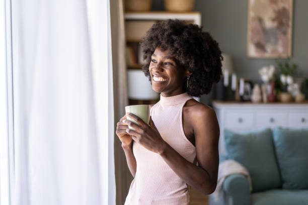 istock Cheerful woman standing by a window 2197517865