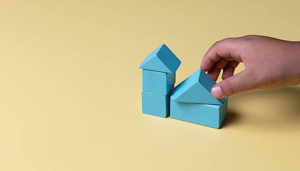 istock Hand building house with wooden blocks on yellow background 2197518064