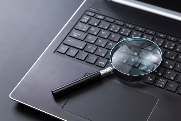 istock Laptop and magnifying glass on a black background 2197523673