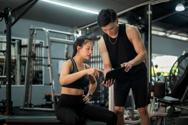 istock A beautiful and fit Asian female client discussing her workout program with her fitness trainer. 2197525298