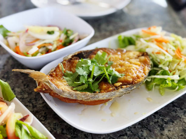 Fried mackerel fish with fresh vegetable salad on the table