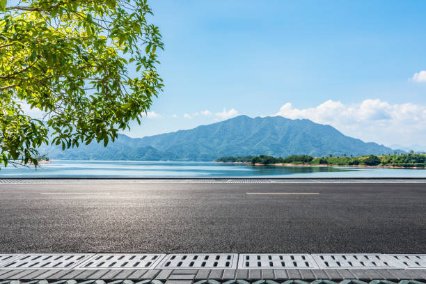 istock Asphalt road and blue lake with mountain nature landscape under blue sky 2197530384