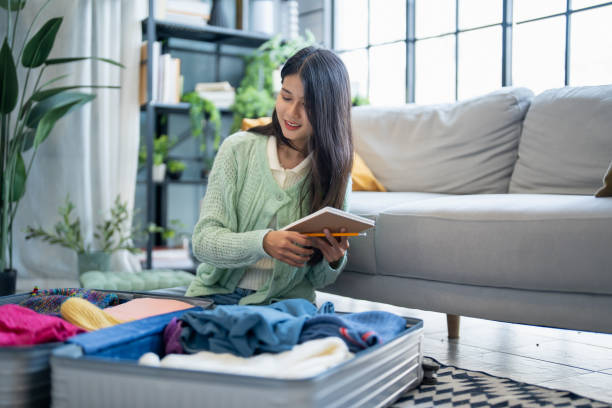 istock Happy asian Woman doing checklist for packing suitcase before holidays trip. 2197530795