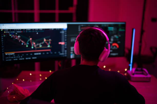 istock Individual focused on stock trading at a desk with dual monitors during evening hours 2197537268