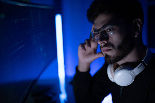 istock Focused individual working on a computer while wearing headphones in a dimly lit room at night 2197537428