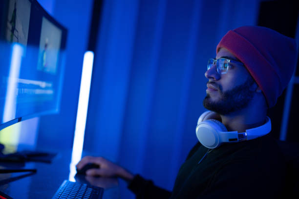 istock Young man working late at night on a computer in a blue-lit workspace with headphones 2197537558