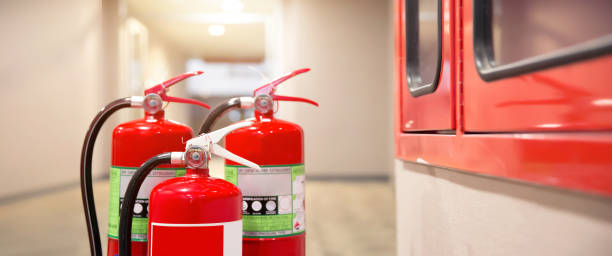 istock Close-up the red fire extinguishers tank at the exit door in the building concepts for emergency safety fire prevention rescue and fire services. 2197539689