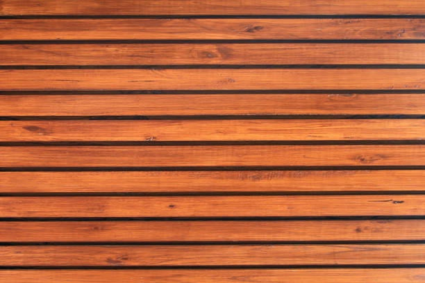 Fine brown wood paneling on the exterior wall of a building. The timber boards are mounted as a house facade. The full frame texture can be an abstract background.