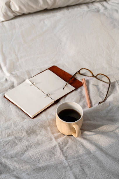 istock Open planner, glasses, and coffee mug on a cozy bed, symbolizing productive mornings and relaxation 2197540968