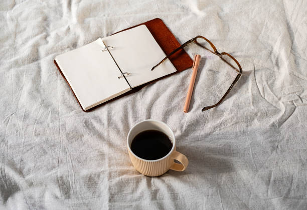 istock Open planner, glasses, and coffee mug on a cozy bed, symbolizing productive mornings and relaxation 2197540970
