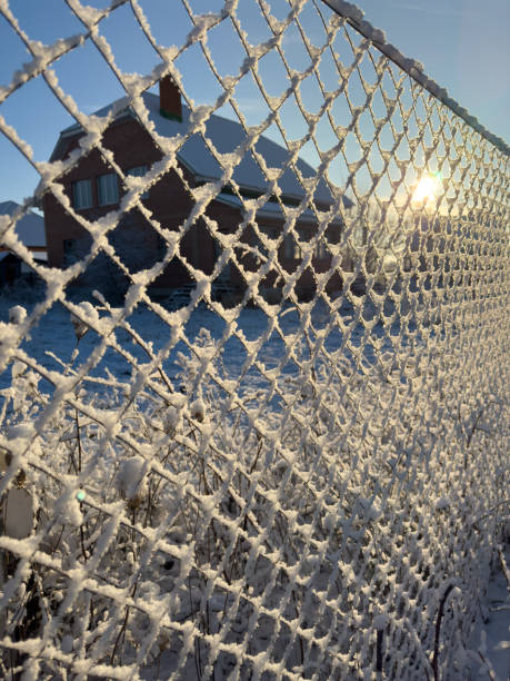istock A fence covered in snow with a house in the background 2197542113