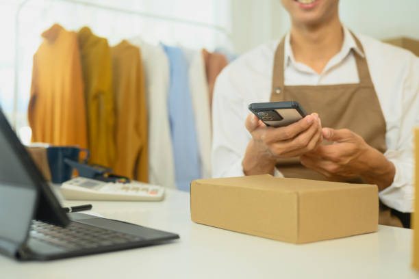 istock Smiling young entrepreneur checking orders on his smartphone while sitting at a workspace 2197543009