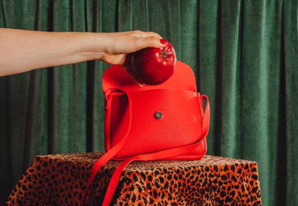 istock A woman's hand takes out a red apple from a red handbag 2197544094