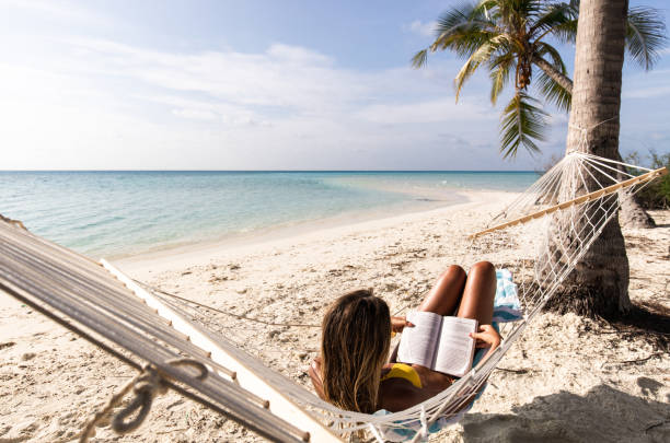 istock Relaxed woman reading a book in hammock on the beach. 2197544705
