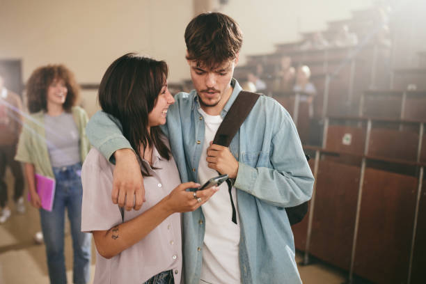 istock Happy university couple using mobile phone in lecture hall. 2197545937