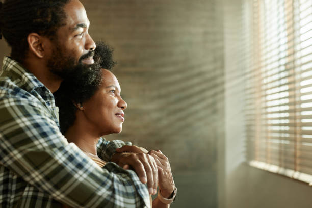 istock Happy black couple day dreaming embraced at home. 2197547140