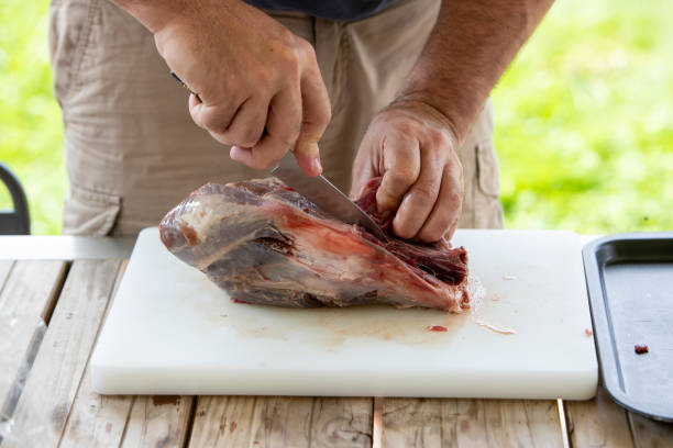 istock Man cutting a piece of wild boar meat. 2197548173