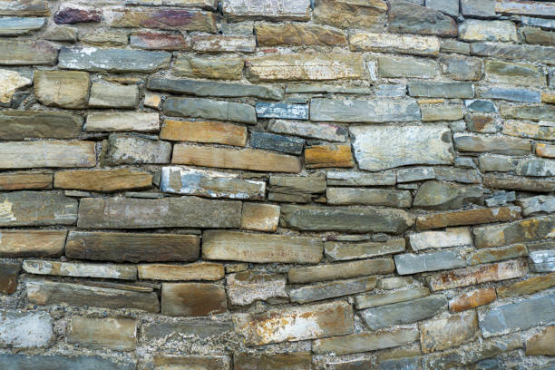 An old wall made of rectangular sandstones of different sizes and colors. The joints, cracks and texture are visible.