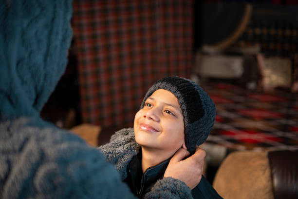 Caring Indian mother putting warm cap on son’s head and getting ready for winter activities.
