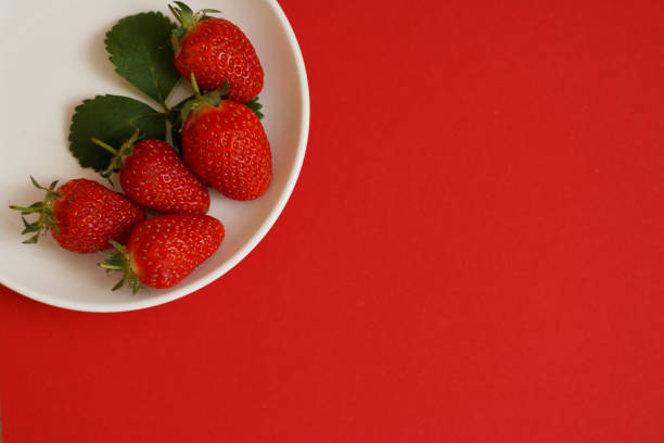 close up of strawberries in a bowl on a white background with negative space