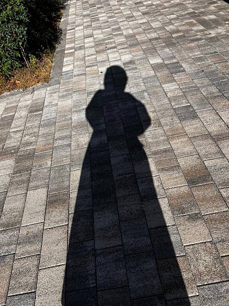 istock The silhouette of a person cast on a textured surface, their form slightly distorted by the angle of light. The shadow creates a mysterious and intriguing composition. 2197551855