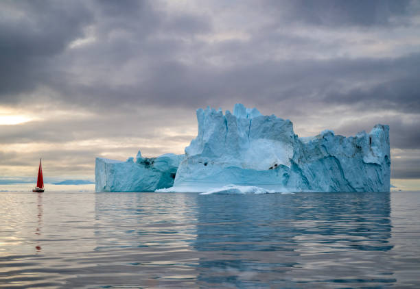 istock red sailboat sailing among floating icebergs in Disko Bay glacier with sunset during polar summer midnight solar season. Ilulissat, Greenland 2197552854