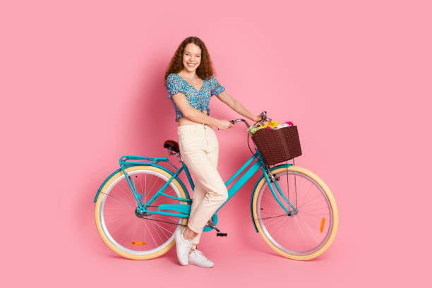 istock Smiling woman with a bicycle against pink background 2197553838